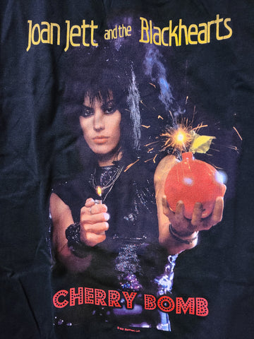 black tee printed band name Joan Jett and the Blackhearts in yellow Joan Jett holding a cherry bomb and a lighter says cherry bomb
