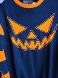 Black knit sweater with orange jack o lantern face and orange striped sleeves